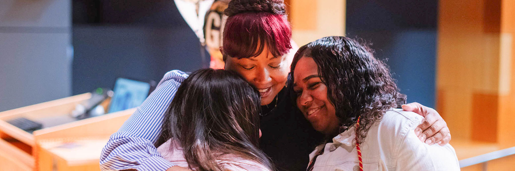 An IUPUI staff member gives two students a loving hug.