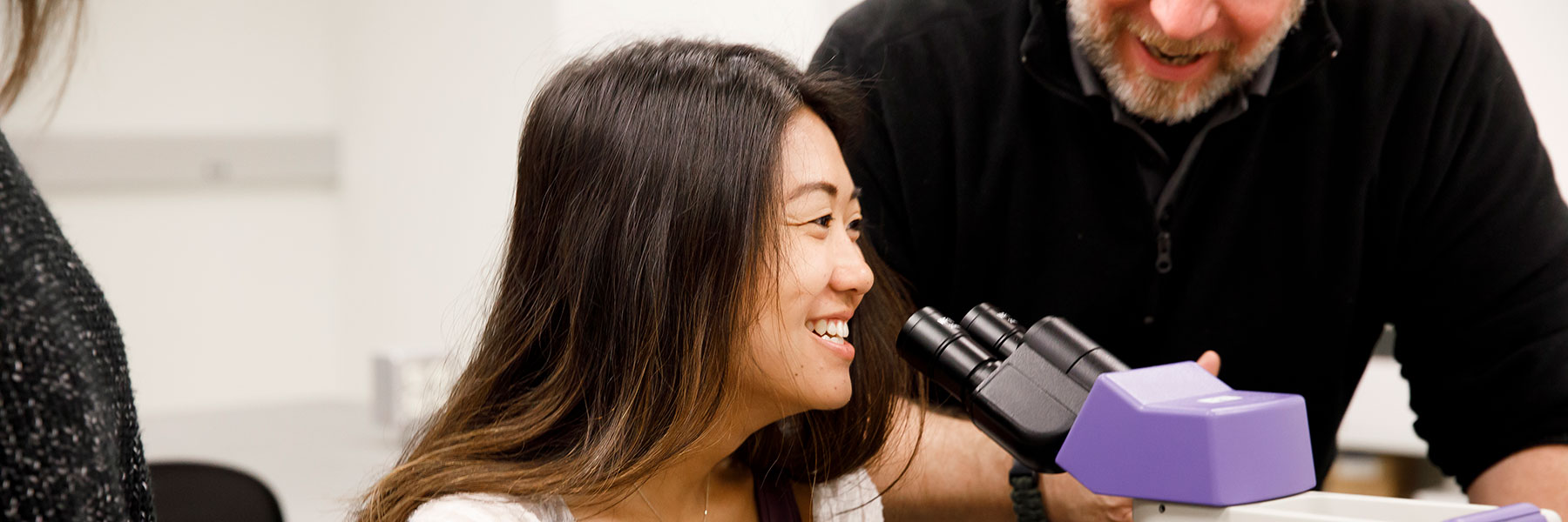 An IUPUI student looking through a microscope.